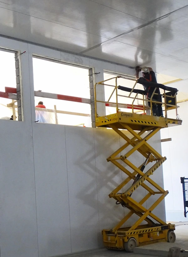 L'image montre l'installation de murs, cloisons et plafonds industriels par Panelconstruct